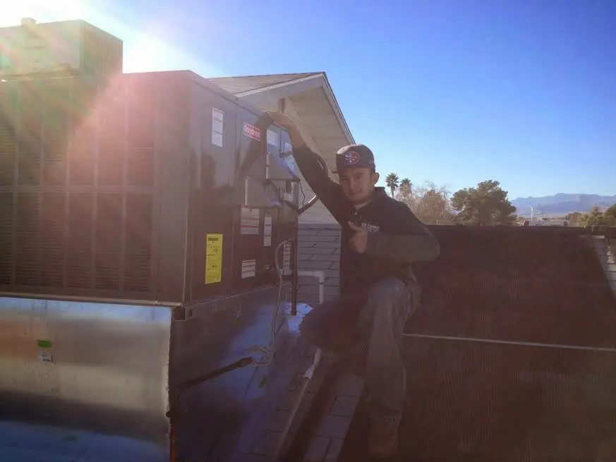 HVAC technician performing Air Duct Cleaning on a rooftop unit in Oak Brook
